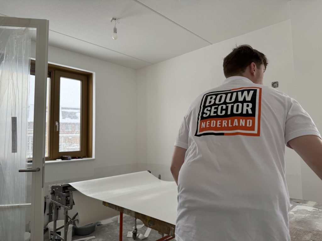 Behanger van Bouwsector Nederland bij de plaktafel met een baan vliesbehang