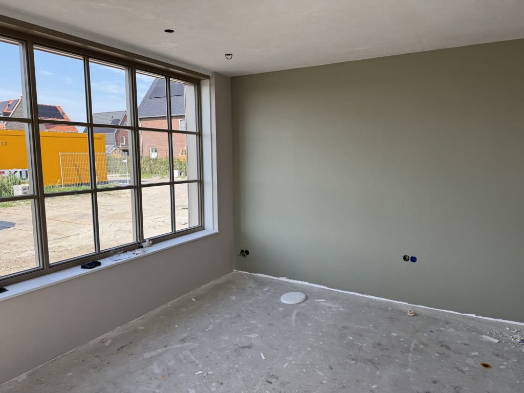 Nieuwbouwkamer met een wand in een grijsgroene kleur naast een groot raam