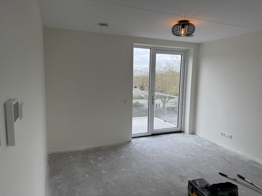 Lichte nieuwbouwkamer met balkondeuren, kort na de afwerking van de wanden